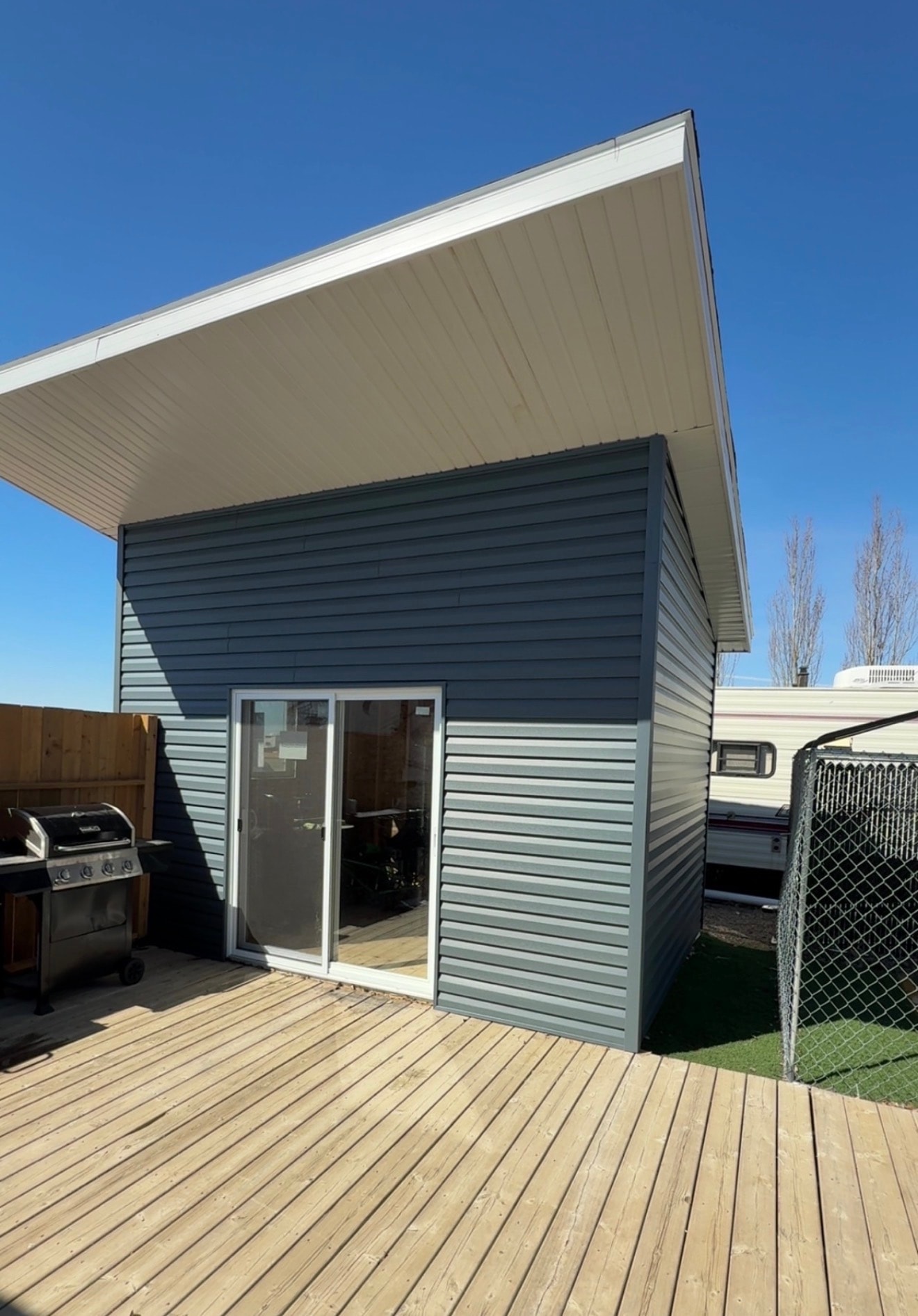 Blue-grey vinyl siding on modern structure with white soffit — BWK Exteriors Regina